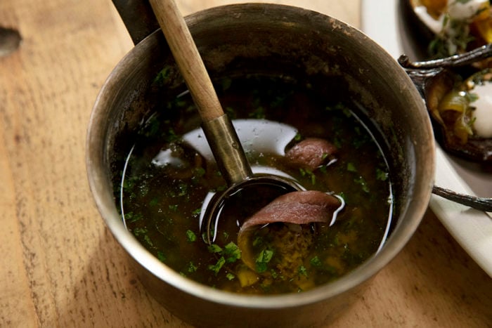 Bagna cauda with Italian parsley and floating Spanish anchovy in a saucepan.